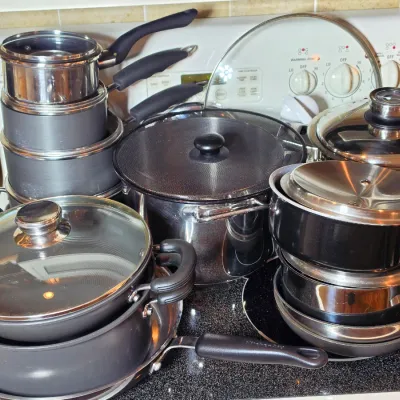 Assorted stainless steel and non-stick cookware set, including pots, pans, and lids in various sizes.