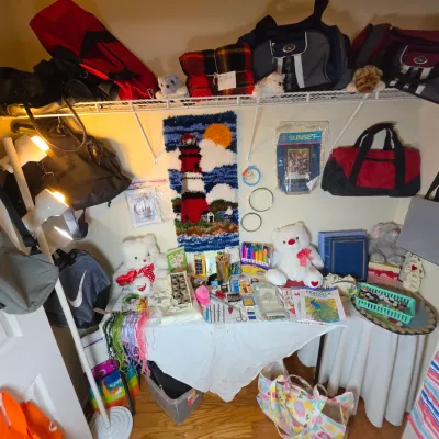 Assorted crafting supplies, duffel bags, and plush toys displayed on tables and shelves in a closet space.