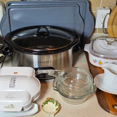 Assorted kitchen appliances and cookware, including a stainless steel Crock-Pot slow cooker, a George Foreman Lean Mean Fat Reducing...