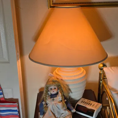 Vintage plaster table lamp with a textured, ribbed base and a large conical shade, shown illuminated on a nightstand next to a porcelain...