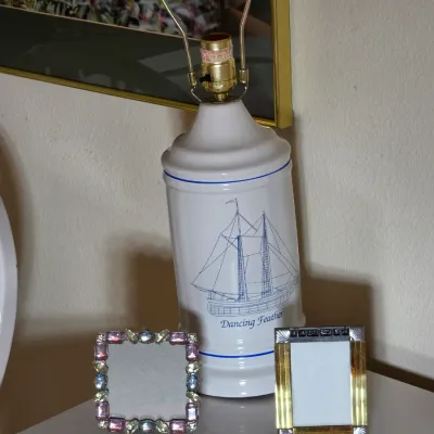 Vintage white ceramic table lamp featuring a blue illustration of the sailing ship 'Dancing Feather', shown alongside two small...