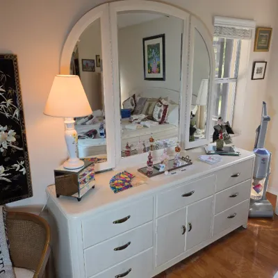 Postmodern white laminate dresser featuring a large three-panel arched mirror, brass-tone hardware, and matching nightstand, circa 1980s.