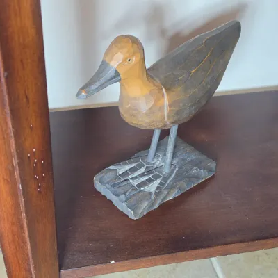Hand-carved wooden shorebird figurine with a faceted finish, mounted on a carved wooden base.