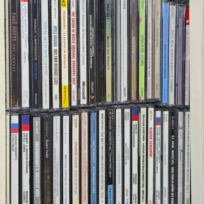Large collection of music CDs in jewel cases, featuring classical, country, and pop artists, organized on shelves.