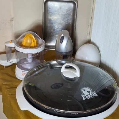 George Foreman Fusion Grill with glass lid, shown alongside a Black & Decker CitrusMate juicer and other small kitchen appliances.