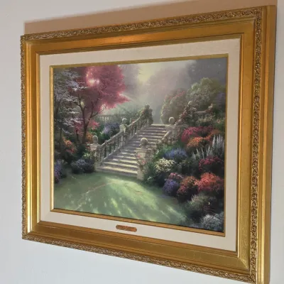 Thomas Kinkade framed canvas print depicting a lush garden staircase, housed in an ornate gold-finished frame with a linen liner.