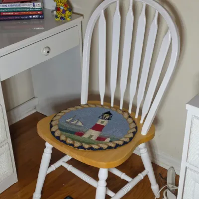 Two-tone Windsor-style wooden chair with a white frame and natural wood seat, featuring a round hooked rug cushion depicting a lighthouse...