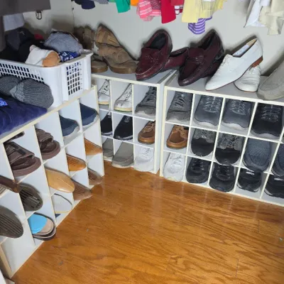 Assorted men's and women's shoes, including loafers, sneakers, and sandals, organized in white cubby shelving units.