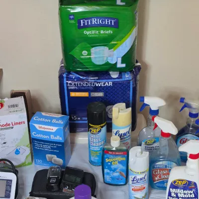 Assortment of household cleaning supplies, personal care items, and medical accessories, including FitRight briefs, Lysol spray, glass...