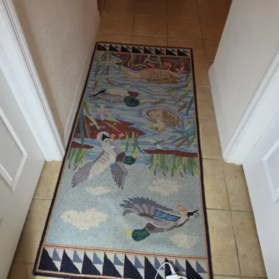 Hand-hooked wool runner rug featuring a detailed waterfowl and marsh scene with mallards in flight and swimming, bordered by a geometric...