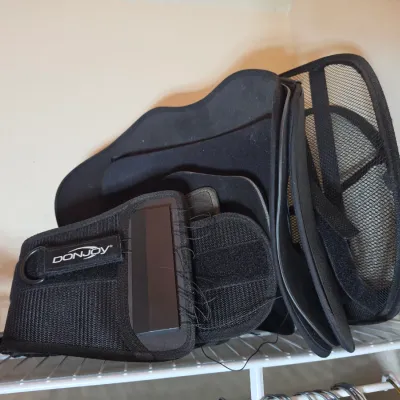 DonJoy black orthopedic back brace with adjustable straps, resting on a wire closet shelf.