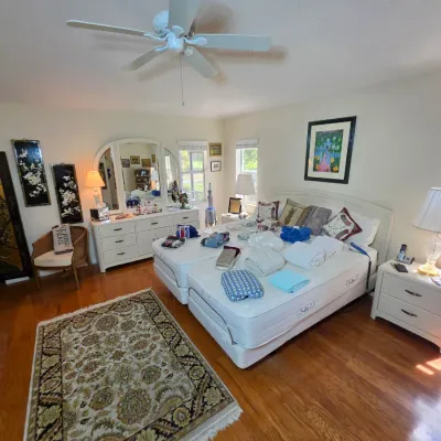 White laminate bedroom set including a triple-mirror dresser, two nightstands, and a headboard, paired with an adjustable split-king bed,...