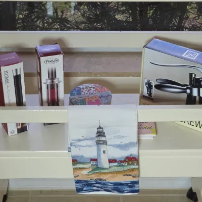 Assorted barware accessories in original packaging, including a lever corkscrew and wine openers, displayed on a white wooden cart...
