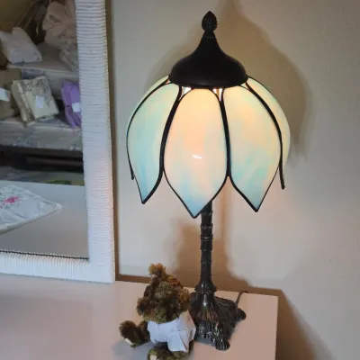 Vintage slag glass tulip lamp with a dark metal base, shown illuminated next to a small teddy bear.