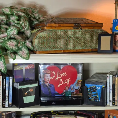 A collection of home media including DVD and Blu-ray box sets, such as "I Love Lucy" and "Seinfeld," arranged on a...