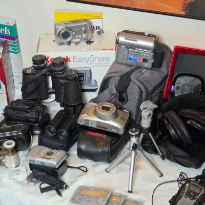 Assortment of vintage electronics and optics, including a Samsung digital camcorder, Pentax film camera, multiple pairs of binoculars, a...