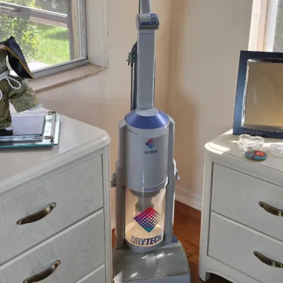 Kenmore Drytech upright vacuum cleaner, positioned between two white laminate nightstands featuring brass-tone handles.