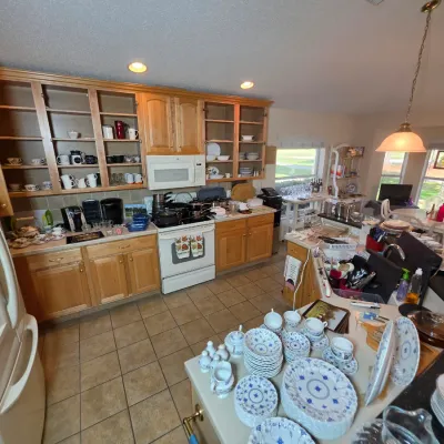 A wide selection of kitchenware, including blue and white china, glassware, and small appliances, displayed on countertops and in oak...