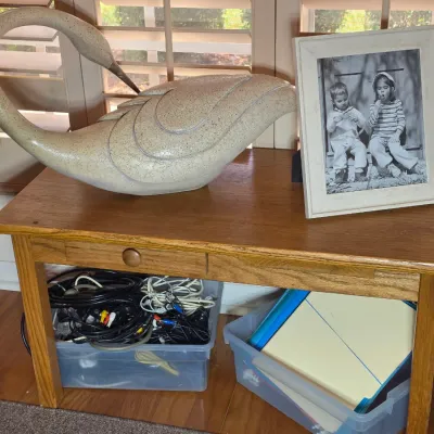 Mid-century modern style ceramic swan sculpture with a speckled glaze, displayed on a wooden side table alongside a framed black and...