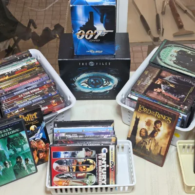 Collection of DVDs and box sets, including The X-Files, James Bond 007, and various movie titles organized in plastic baskets.