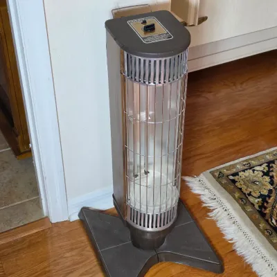 Vintage quartz tower space heater with a brown and silver finish, featuring a protective wire grille and top-mounted control dial.