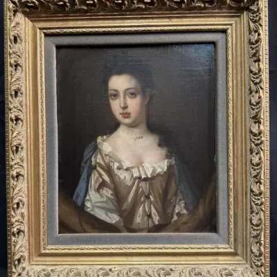 Antique oil portrait of a young woman in 18th-century style attire, housed in an ornate, gilded gesso frame with a fabric liner.