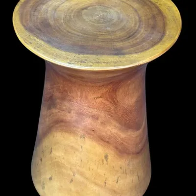 Carved solid wood pedestal side table or stool, featuring a flared top and base with prominent natural grain patterns.