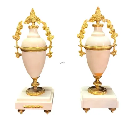 Pair of Neoclassical style pink marble and gilt bronze urns, featuring ornate floral handles and square plinth bases.