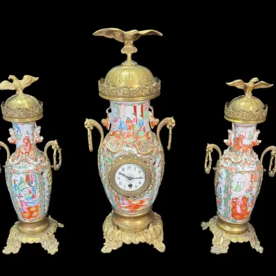 Antique French or Chinese export style three-piece clock garniture set, featuring a central porcelain urn clock and two matching side...