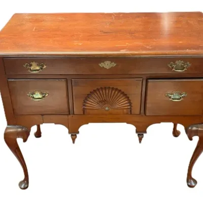 Queen Anne style cherry lowboy featuring a fan-carved center drawer, brass batwing pulls, and cabriole legs ending in pad feet.