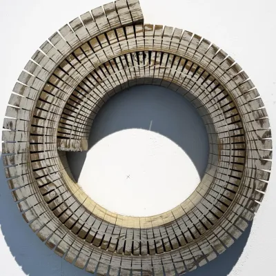 Spiral-shaped wooden wall sculpture featuring a slatted, segmented design with a weathered, whitewashed finish.