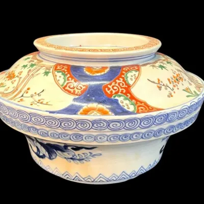 Japanese Imari porcelain covered bowl, featuring hand-painted floral and geometric motifs in cobalt blue, rust, and green on a white ground.