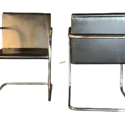 Pair of mid-century modern cantilever armchairs featuring black vinyl upholstery and tubular chrome frames, shown from front and back views.