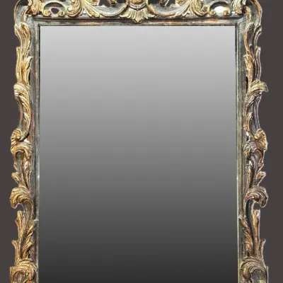 Ornate Baroque-style wall mirror featuring a heavily carved giltwood frame with scrollwork and a prominent shell crest.