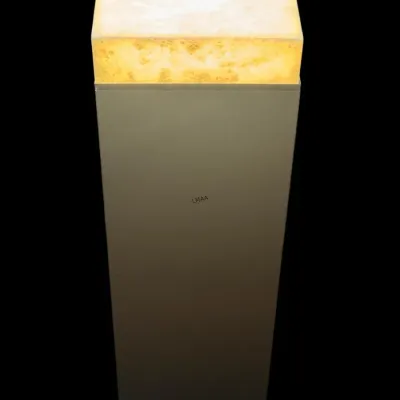 Modern minimalist pedestal featuring a glowing, illuminated alabaster or onyx top on a tall, square column base.