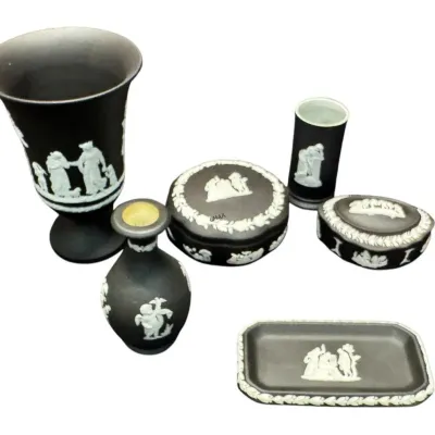 Six-piece collection of black Wedgwood jasperware, including vases, lidded trinket boxes, and a small rectangular tray, all featuring...