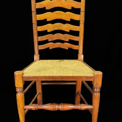Vintage ladder-back side chair featuring a woven rush seat, turned legs, and a decorative front stretcher.