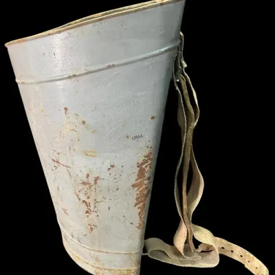 Vintage metal berry picking bucket with a curved back and adjustable canvas shoulder strap, showing significant rust and wear.