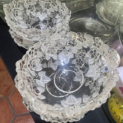 Two stacks of vintage pressed glass bowls featuring a raised floral and leaf pattern with frosted accents.