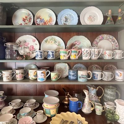 A collection of vintage and collectible ceramics, including floral plates, patterned mugs, teacups, and decorative pitchers, displayed on...