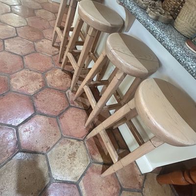 Set of four rustic light oak barstools with round seats and footrests, showing light wear.