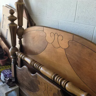 Vintage wooden four-poster bed frame featuring a curved headboard and footboard with decorative scrollwork and turned posts.