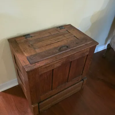Rustic wooden storage chest with a hinged lid, metal hardware, and paneled front, showing natural wear and grain.