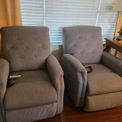 Pair of modern power lift recliners in grey textured fabric, featuring button-tufted backrests and wired remote controls.