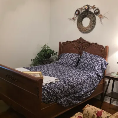 Antique carved wooden bed frame with an ornate headboard and footboard, styled with blue floral bedding.