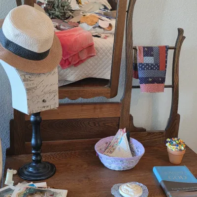 Antique oak vanity with an adjustable mirror, featuring a hat stand, a woven basket, and various decorative accessories.