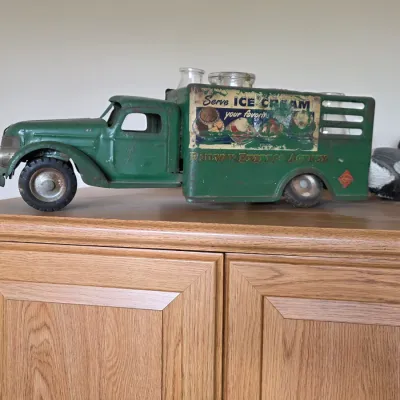 Vintage green pressed steel toy delivery truck featuring "Railway Express Agency" and "Serve Ice Cream" decals,...