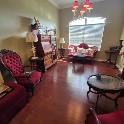 Victorian-style parlor furniture set featuring tufted burgundy velvet armchairs, a matching settee, a wooden secretary desk, and various...