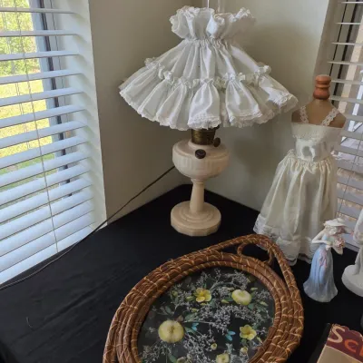 Vintage electric hurricane-style table lamp with a ruffled white fabric shade, displayed alongside a miniature dress form, a small...