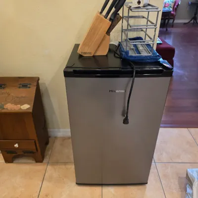 Hisense stainless steel compact mini refrigerator, shown with a Farberware knife block and wire organizer rack on top.
